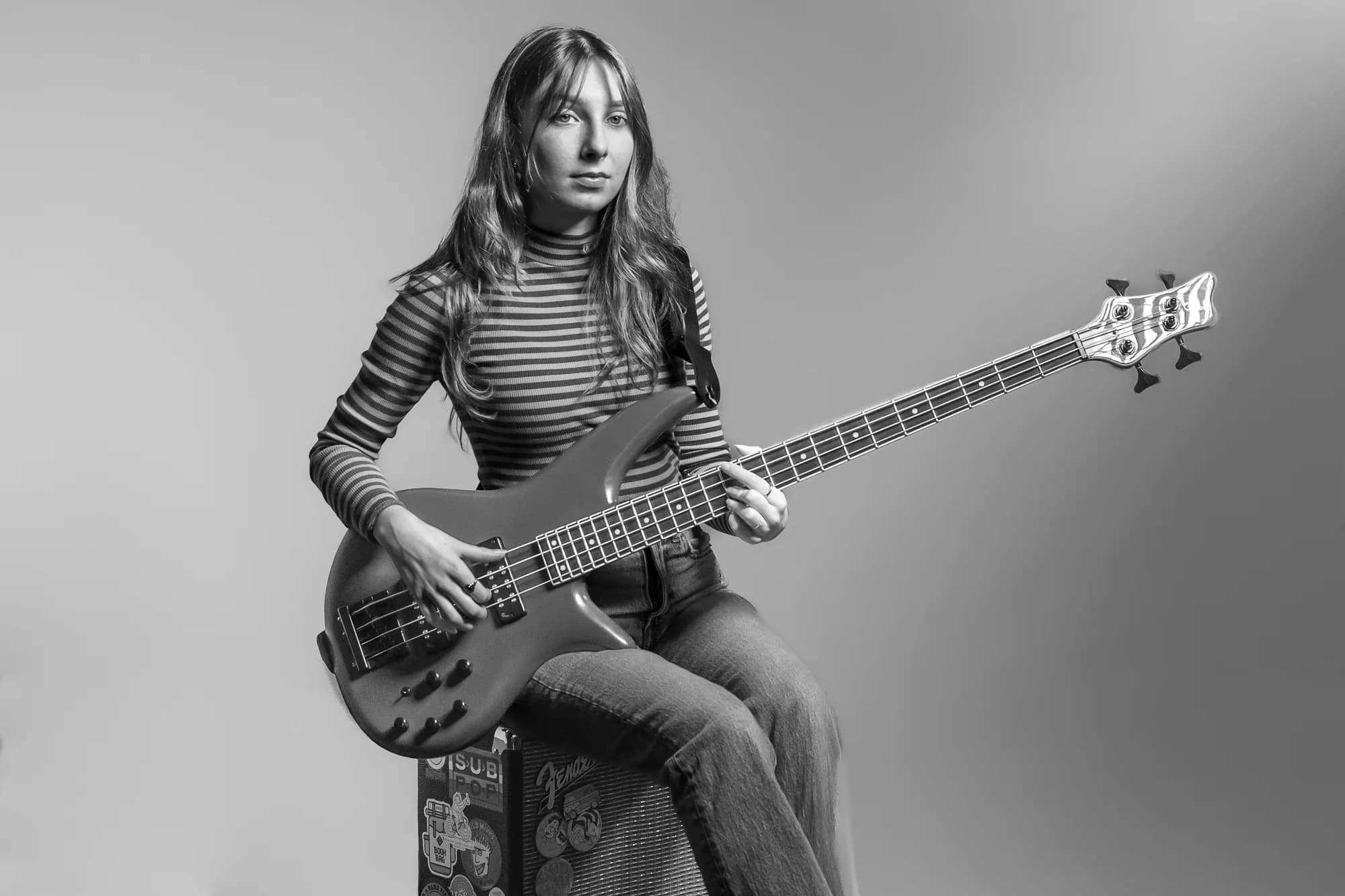Black and white studio portrait of Tori Morley seated with bass.