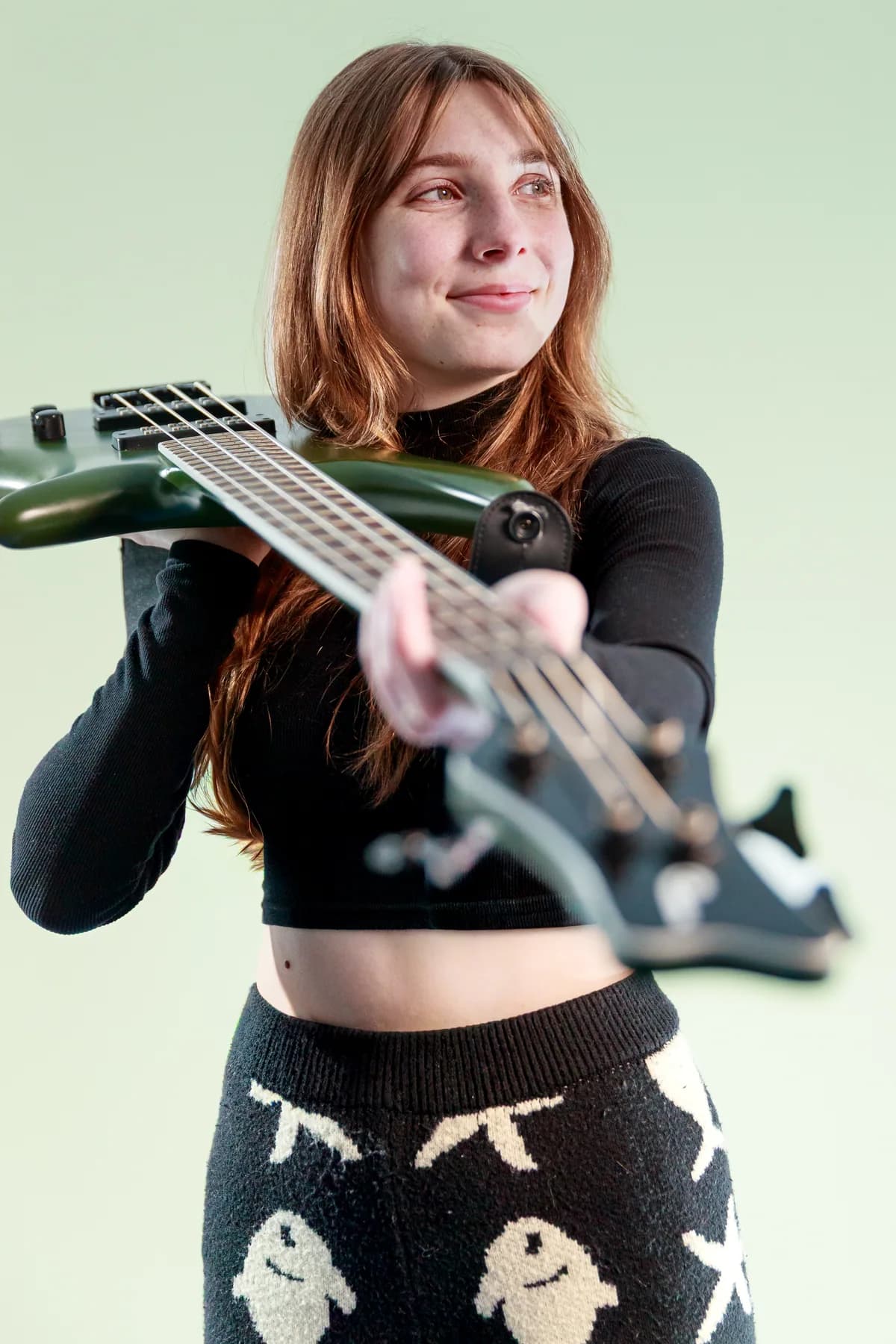 Tori Morley smiling behind the neck of a green bass.